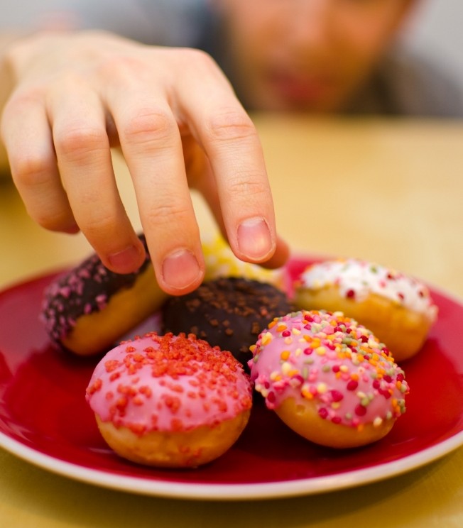 reaching man treats doughnuts unhealthy